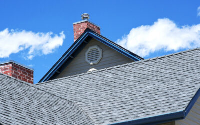 Gray shingled house roofs and gables under a blue sky with scattered clouds